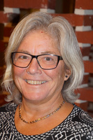 Portræt af en smilende kvinde med gråt hår og briller.