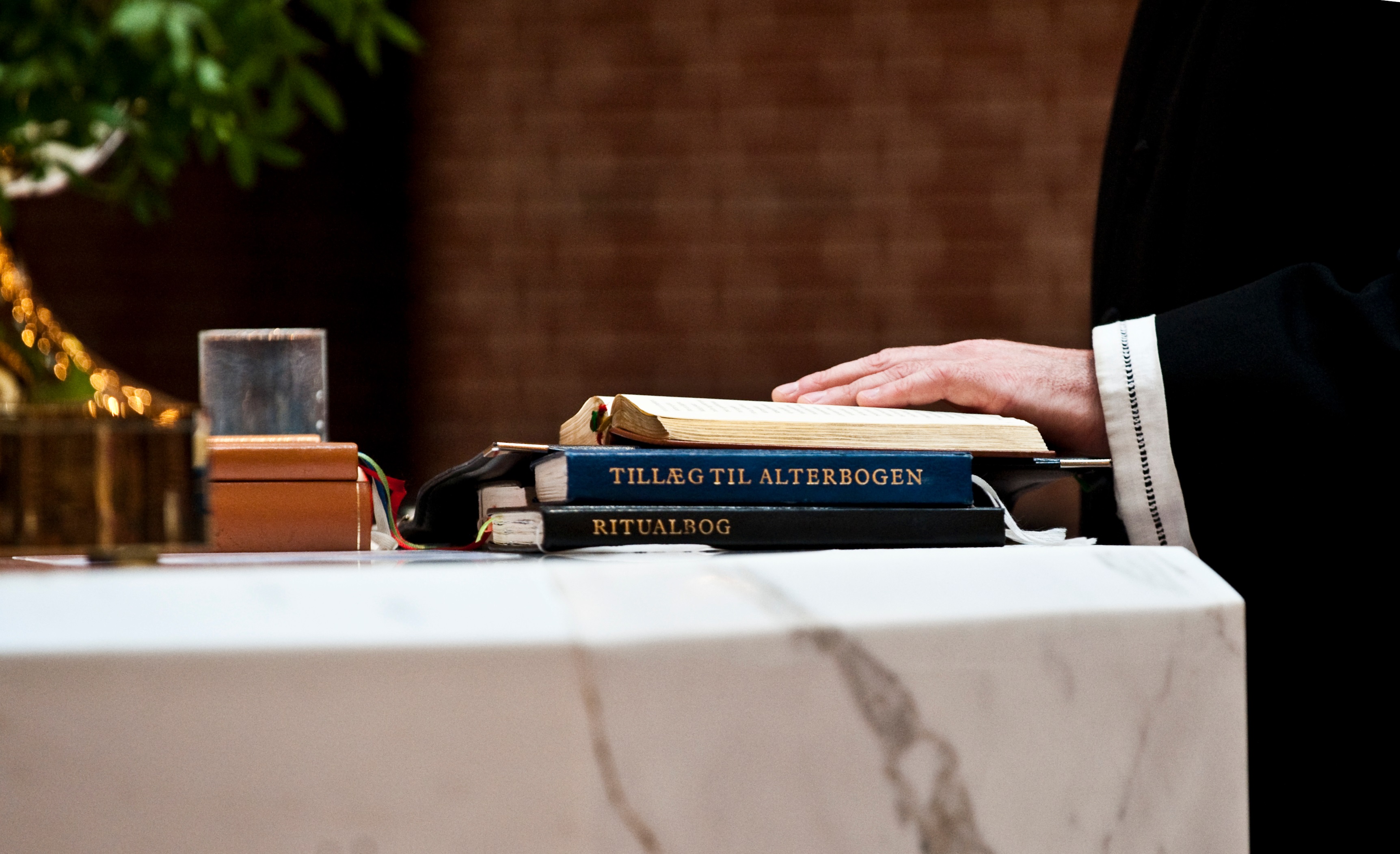 Et moderne kors af hvide rør på en murstenskirkemur.