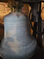 En nærbillede af en stor kirkeklokke med inskription.