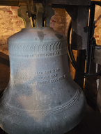 En nærbillede af en stor kirkeklokke med inskription.