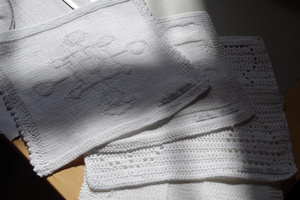 Strikkede hvide firkanter med kristne motiver.