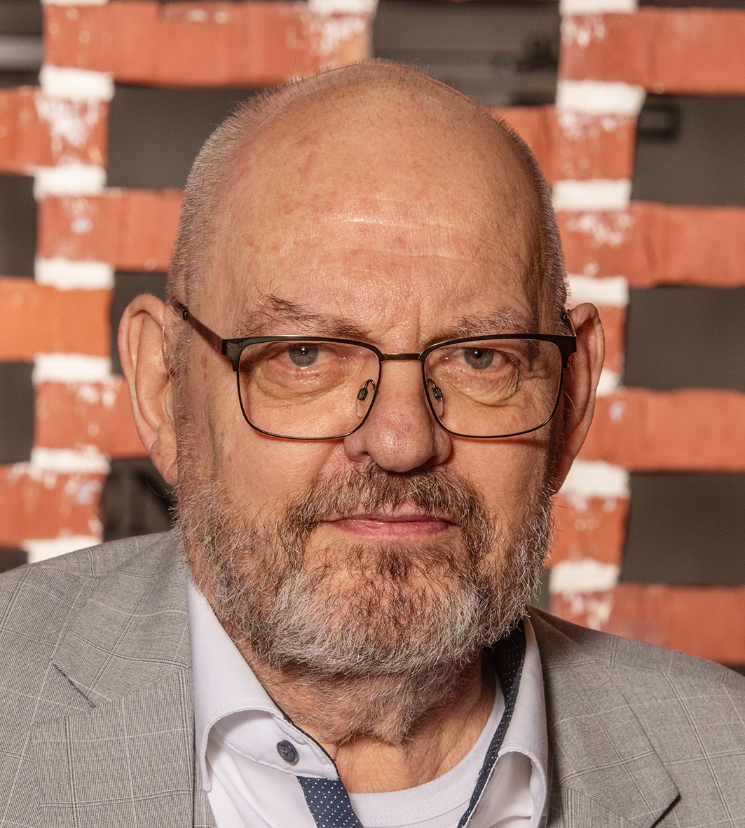 Portræt af en alvorligt udseende mand med gråt hår og en ternet skjorte.