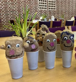 Håndarbejde af jordfyldte strømper med ansigter i kopper.