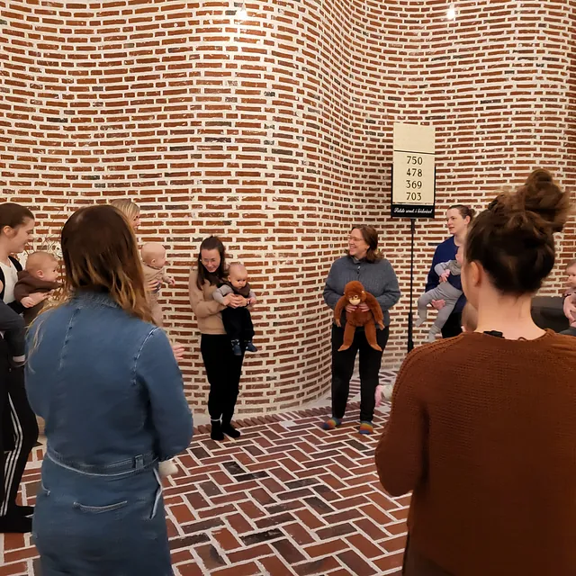 Gruppe af mødre og babyer i et kirkerum.