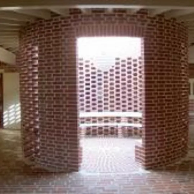 En buet murstensvæg med en åbning og en bænk indeni.