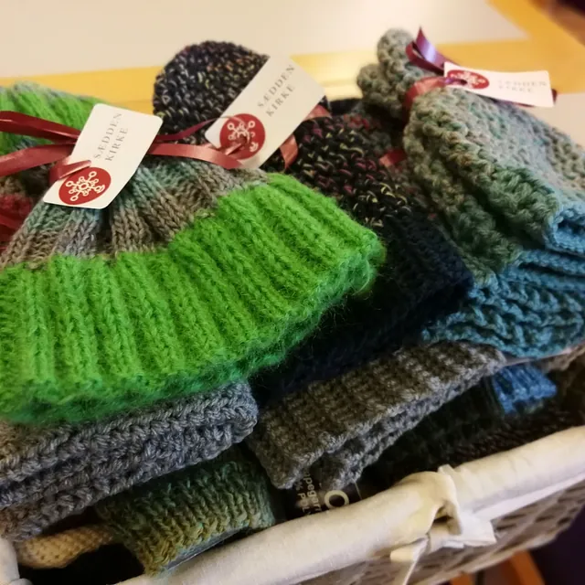 Kurv med strikkede huer med "Sædden Kirke" mærker.